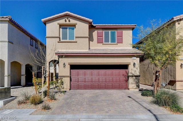 view of front facade featuring a tiled roof, decorative driveway, a garage, and stucco siding