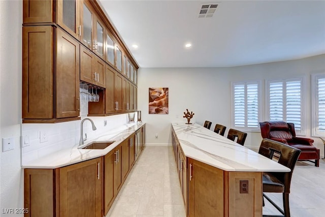 kitchen with light tile patterned flooring, tasteful backsplash, sink, a breakfast bar area, and kitchen peninsula