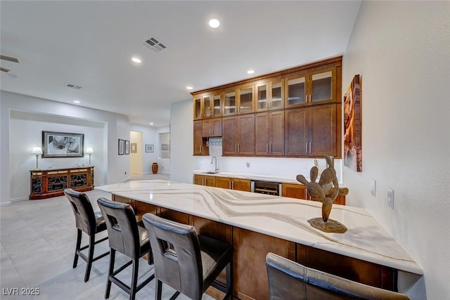 kitchen with wine cooler, a kitchen bar, kitchen peninsula, and sink