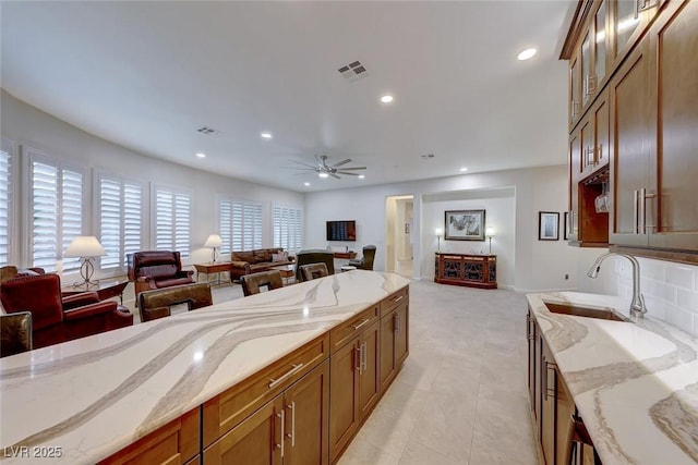 kitchen featuring light stone counters, ceiling fan, sink, and light tile patterned floors