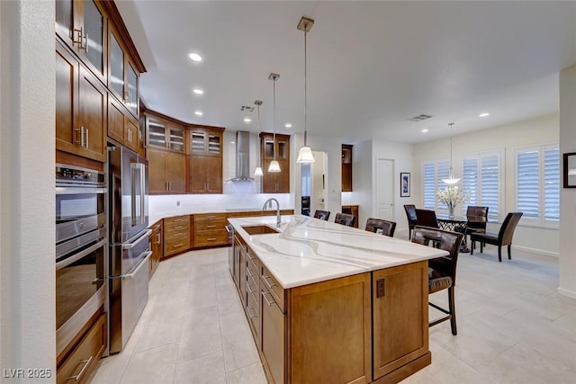 kitchen with pendant lighting, wall chimney range hood, a breakfast bar area, and a spacious island