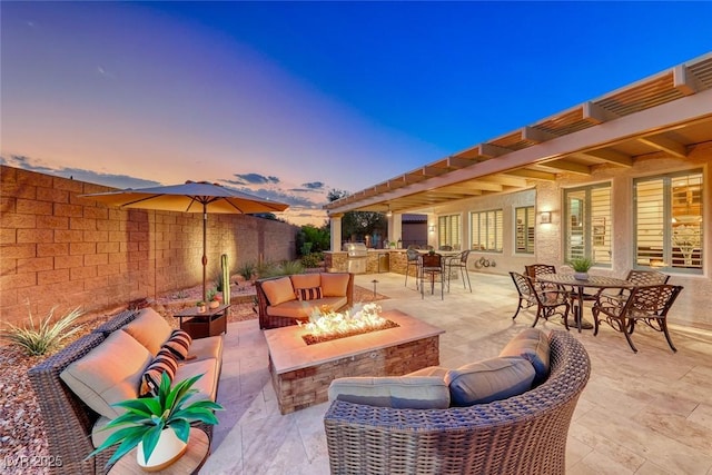 patio terrace at dusk featuring exterior kitchen and an outdoor fire pit