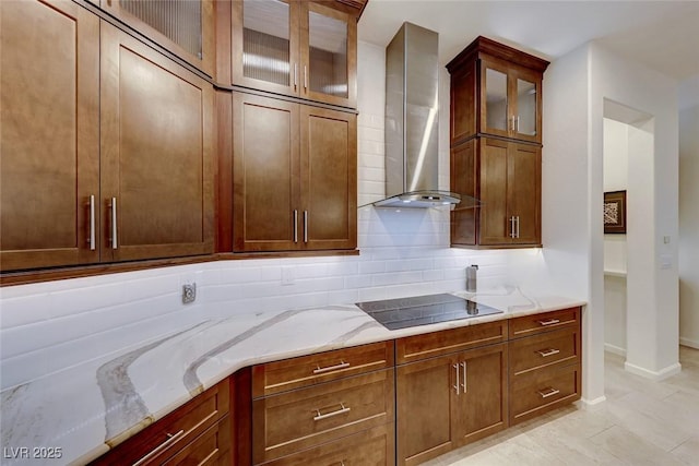 kitchen with black electric cooktop, backsplash, light stone counters, and wall chimney range hood