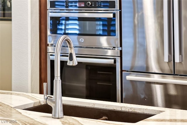 kitchen with light stone counters and appliances with stainless steel finishes