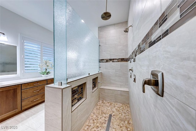 bathroom with vanity, a tile shower, tile patterned floors, and tile walls