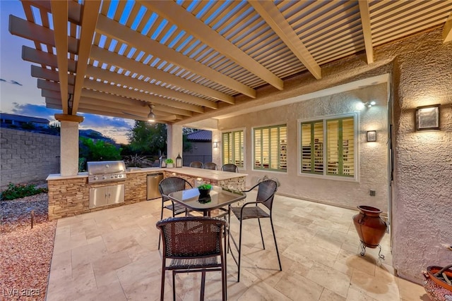 patio terrace at dusk featuring area for grilling, a pergola, and exterior kitchen