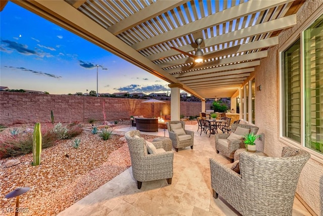 patio terrace at dusk featuring outdoor lounge area, ceiling fan, and a pergola