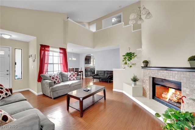 living area with a chandelier, a fireplace, wood finished floors, and baseboards