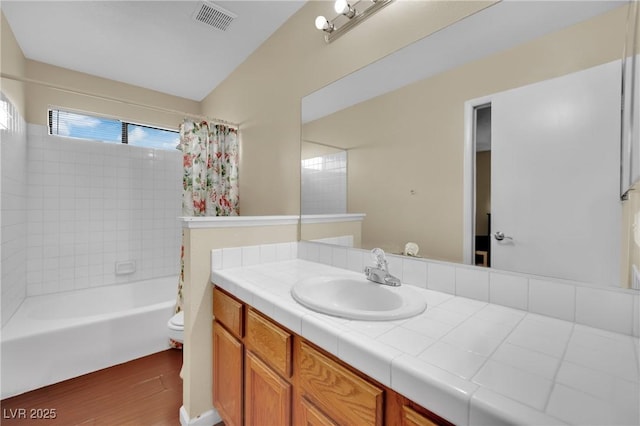 full bathroom featuring toilet, wood finished floors, vanity, visible vents, and shower / tub combo with curtain