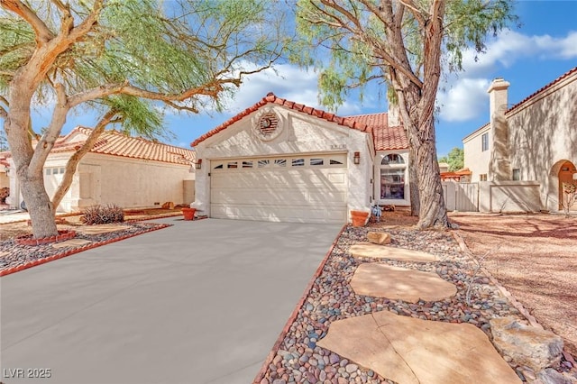 mediterranean / spanish-style house with an attached garage, fence, a tile roof, concrete driveway, and stucco siding