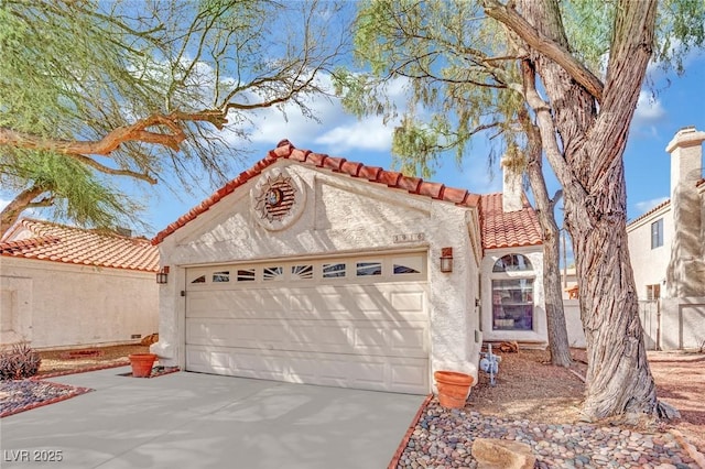 mediterranean / spanish home featuring a garage, a tiled roof, driveway, and stucco siding