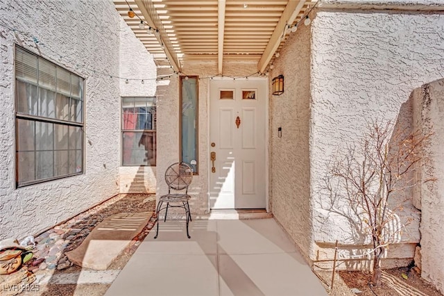 entrance to property with a patio and stucco siding