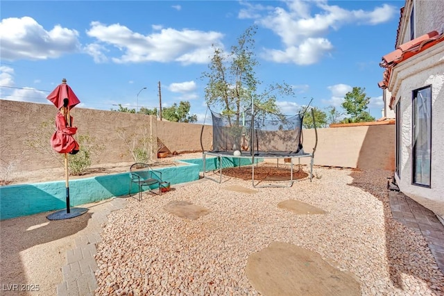 exterior space featuring a trampoline, a patio area, and a fenced backyard