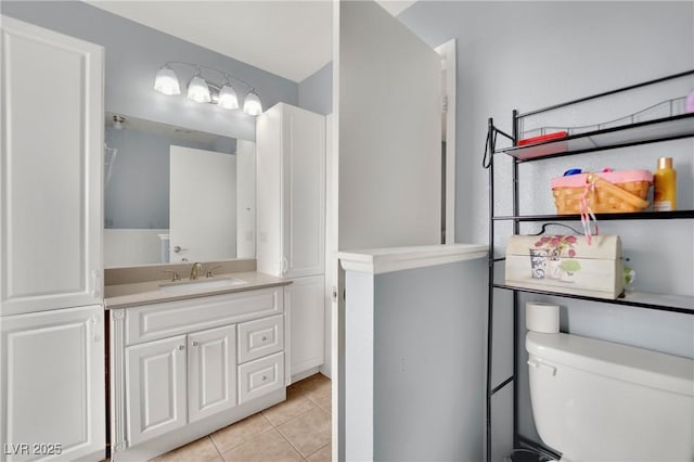 bathroom with toilet, vanity, and tile patterned floors