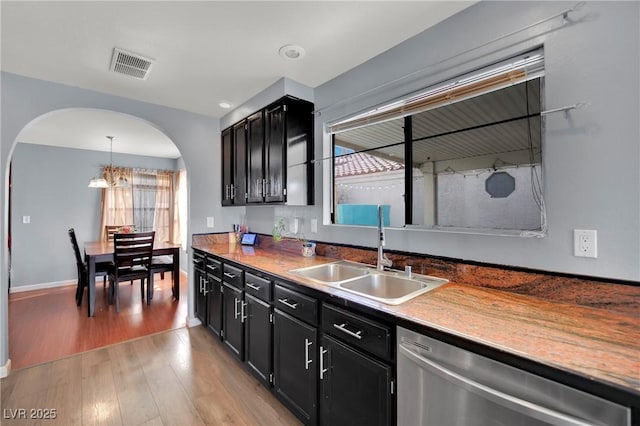 kitchen with dishwasher, dark cabinetry, a sink, and visible vents