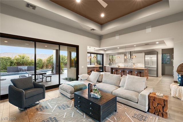 living room featuring a tray ceiling, light wood-type flooring, and a high ceiling