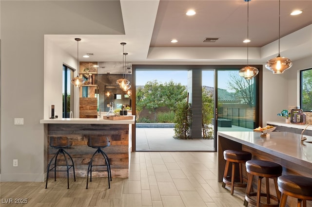 kitchen featuring pendant lighting, a tray ceiling, and a kitchen breakfast bar