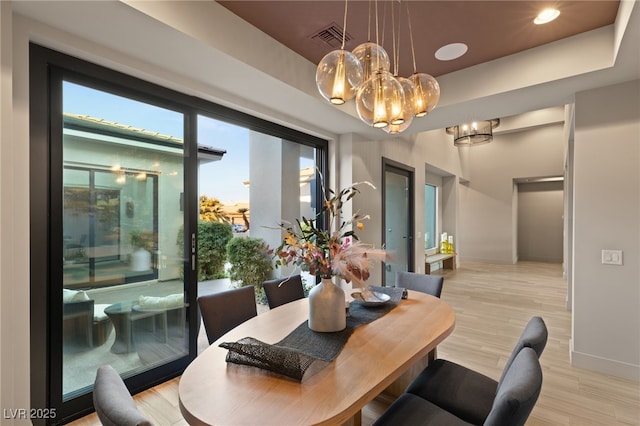 dining space with light hardwood / wood-style flooring and a tray ceiling