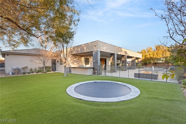 rear view of property with a trampoline, central AC unit, and a lawn