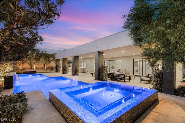 pool at dusk with a patio area, outdoor lounge area, and an in ground hot tub