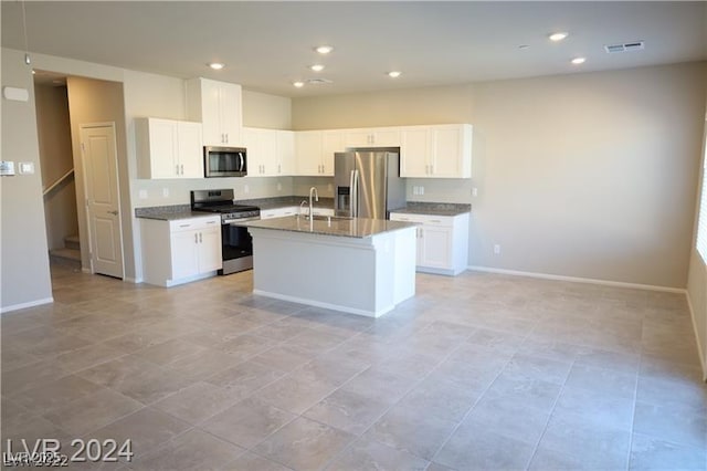 kitchen with sink, appliances with stainless steel finishes, a center island with sink, white cabinets, and stone countertops