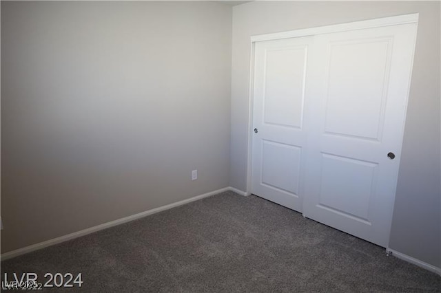 unfurnished bedroom featuring dark carpet and a closet