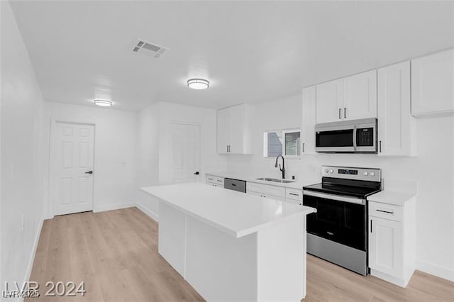 kitchen featuring a kitchen island, sink, white cabinets, light hardwood / wood-style floors, and stainless steel appliances