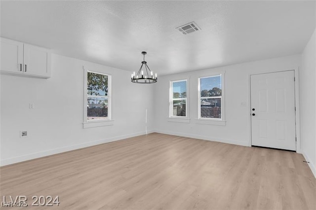 unfurnished dining area featuring a chandelier and light hardwood / wood-style flooring