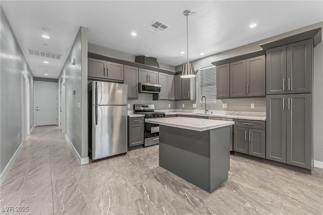 kitchen featuring sink, gray cabinetry, hanging light fixtures, appliances with stainless steel finishes, and a kitchen island