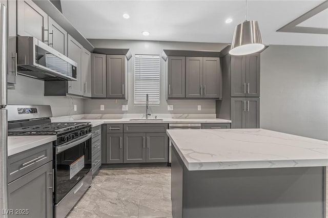 kitchen featuring gray cabinets, pendant lighting, sink, light stone counters, and stainless steel appliances