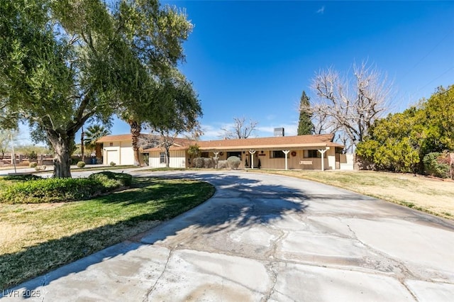 ranch-style home featuring a front lawn and curved driveway