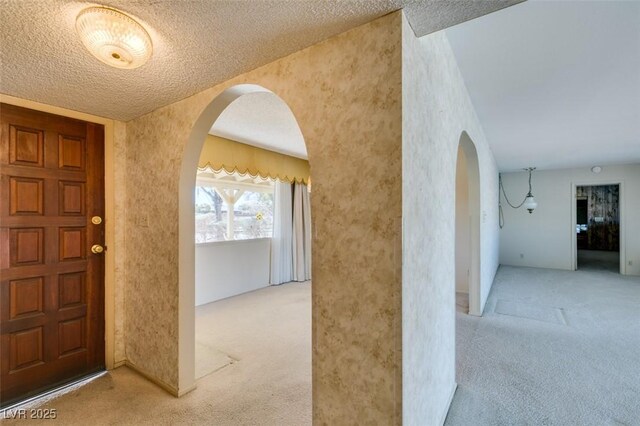 interior space with arched walkways, light carpet, and a textured ceiling