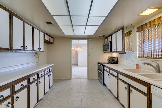 kitchen featuring visible vents, white cabinets, stainless steel appliances, light countertops, and a sink