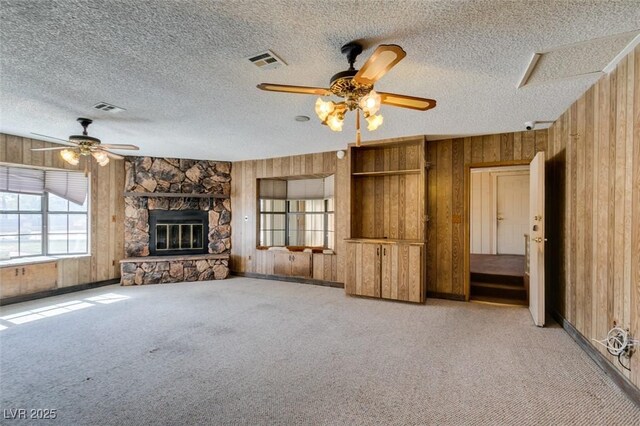 unfurnished living room with light carpet, visible vents, and wooden walls