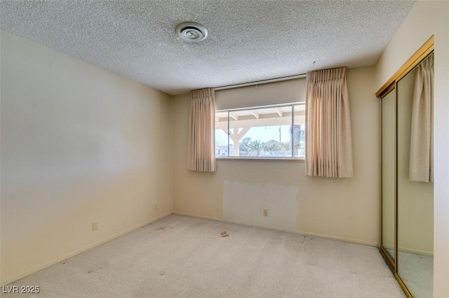 unfurnished bedroom with light carpet, a closet, a textured ceiling, and baseboards