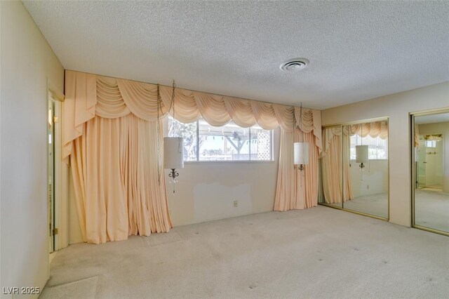 interior space with carpet floors, multiple windows, visible vents, and a textured ceiling