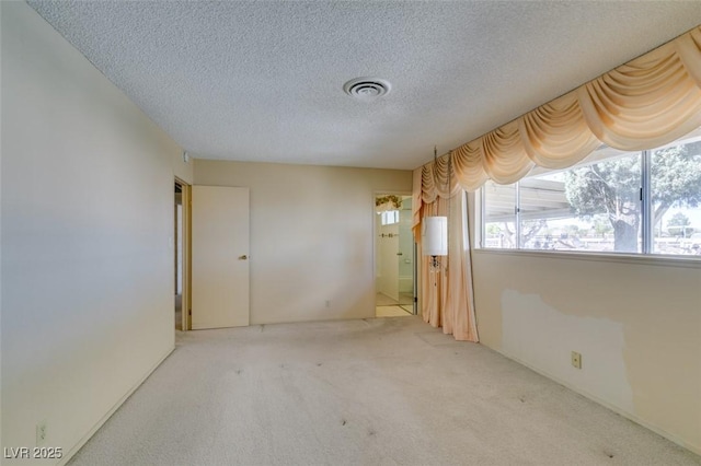 carpeted empty room with visible vents and a textured ceiling