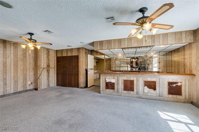 unfurnished living room featuring wood walls, carpet, and visible vents