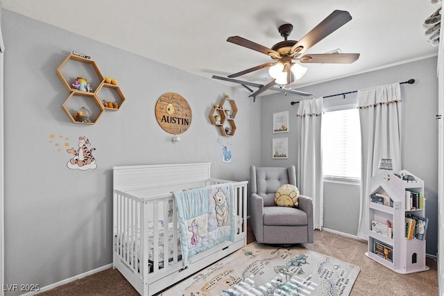 bedroom with a crib, carpet, a ceiling fan, and baseboards