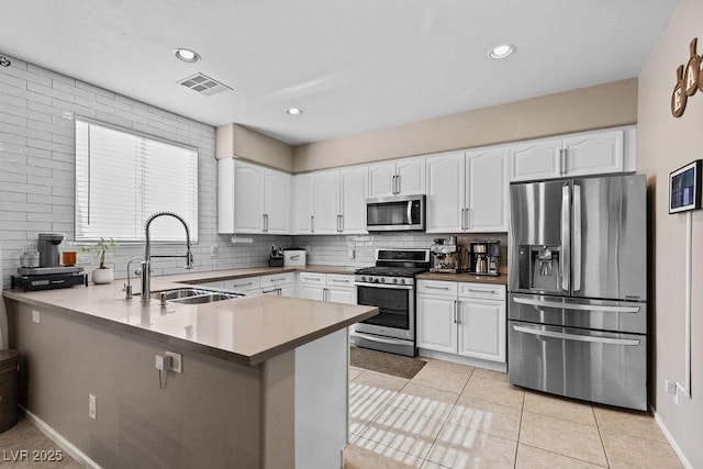 kitchen with stainless steel appliances, light countertops, white cabinetry, and a peninsula