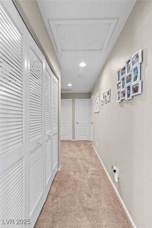 hall featuring recessed lighting, attic access, baseboards, and light colored carpet