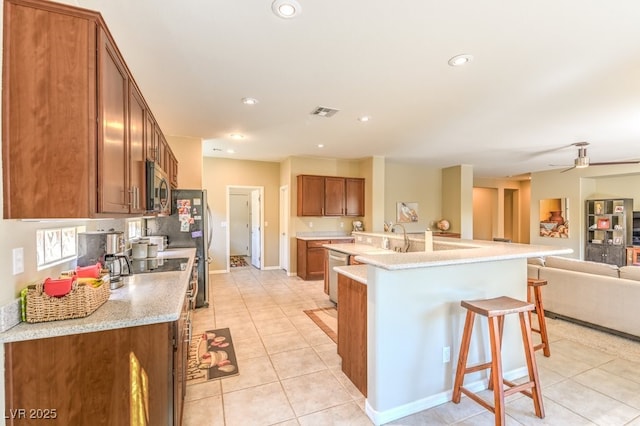 kitchen featuring sink, a kitchen bar, a kitchen island with sink, light tile patterned floors, and stainless steel appliances