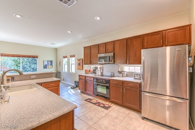 kitchen featuring sink, light tile patterned floors, tasteful backsplash, black appliances, and light stone countertops