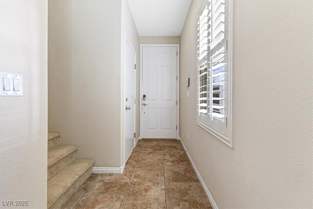 doorway to outside with stairway, baseboards, and tile patterned floors