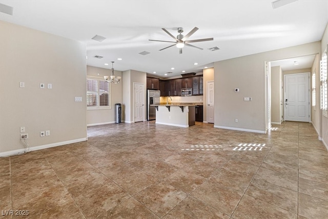 unfurnished living room with plenty of natural light, baseboards, visible vents, and ceiling fan with notable chandelier