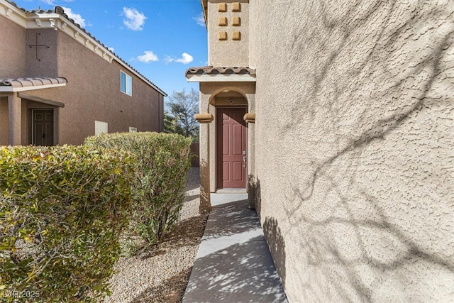 property entrance featuring a tiled roof and stucco siding