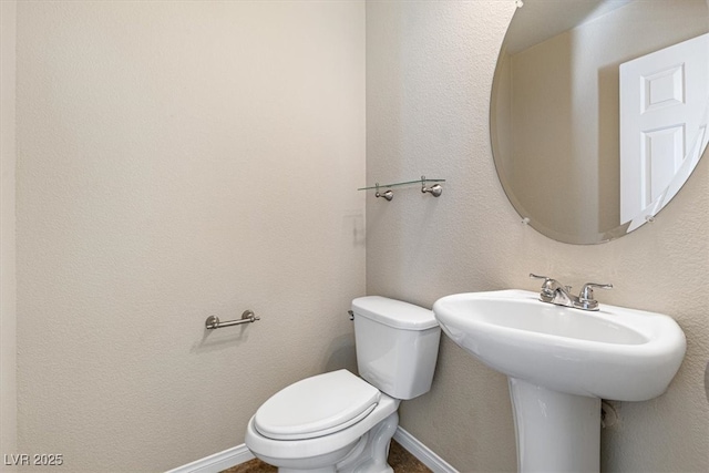 half bath with toilet, baseboards, and a textured wall