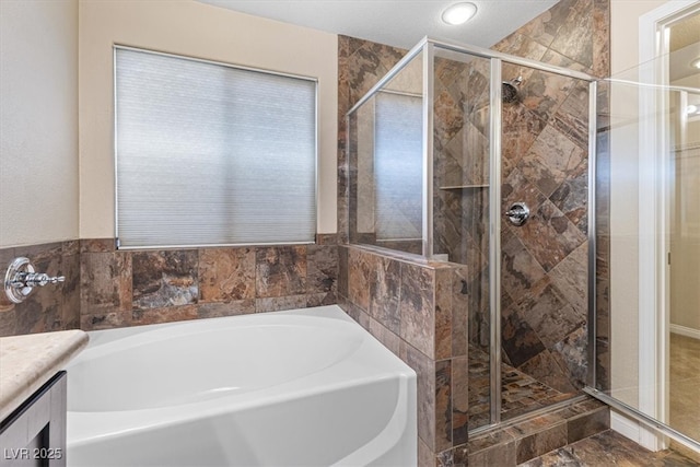 bathroom featuring a stall shower, a bath, and vanity