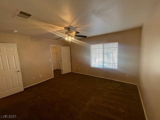 unfurnished bedroom with ceiling fan, dark carpet, and a closet