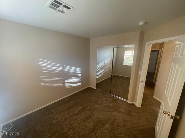 unfurnished bedroom featuring dark carpet and a closet